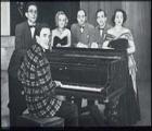 The Logan family grouped round Jimmy seated at the piano (STA JLC PH 180)